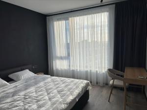 a bedroom with a bed and a desk and a window at Bavaro apartments 5 in Ivano-Frankivsk +4 photos