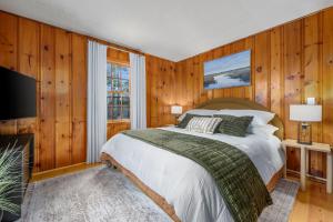 a bedroom with a bed and a tv and wooden walls at The Coast: Cozy Cape Escape in Dennis Port in Dennis Port