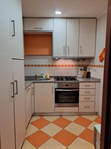 a kitchen with white cabinets and an orange and white floor at Casa da Miquinhas I in Ponte da Barca