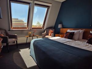 ein Schlafzimmer mit einem Bett, zwei Stühlen und zwei Fenstern in der Unterkunft Hotel Vrouwe van Stavoren in Stavoren