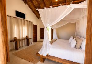 a bedroom with a canopy bed with white pillows at CASA SIMONI Trancoso in Trancoso +59 photos