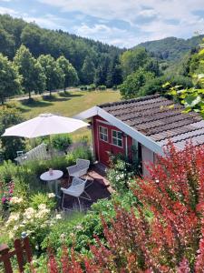 a small red house with an umbrella and a table and chairs at Ferienwohnungen Naheliebe in Bärenbach