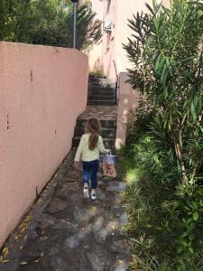 a little girl walking down some stairs with a bucket at Casamea - T2, Piscine, Vue Mer, Clim, Balcon in Porticcio