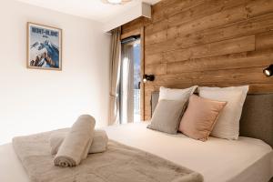 a bedroom with a white bed with a wooden wall at Apartment Leo - 2BR, Modern, Lift access, Mountain views in Les Houches