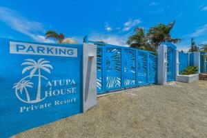 a blue fence with a parking atuana house private resort at Atupa House in Noord