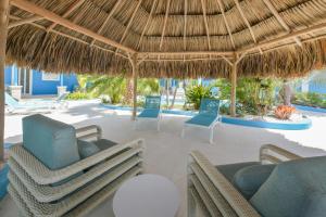 a resort patio with chairs and a thatched umbrella at Atupa House in Noord