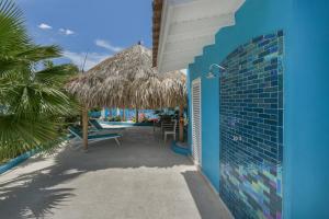 a blue building with a straw umbrella on the beach at Atupa House in Noord