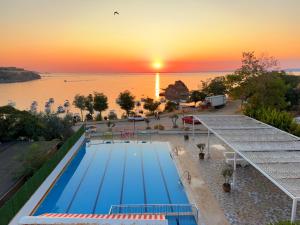 a swimming pool with the sunset in the background at Mercan Otel in Çanakkale