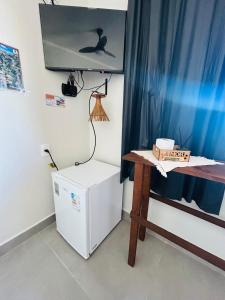 a room with a desk and a refrigerator and a table at Pouso Canastra - Chalés in São João Batista do Glória