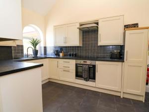 a kitchen with white cabinets and black counter tops at Clwyd Cottage in St Asaph +31 photos