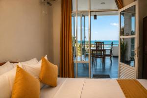 a bedroom with a bed and a view of the ocean at Queens Beach Hotel in Tangalle
