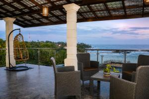 a patio with chairs and a table and a view of the ocean at Queens Beach Hotel in Tangalle