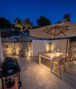 a table and chairs with an umbrella and a grill at Villas Roumeli in Roumelí
