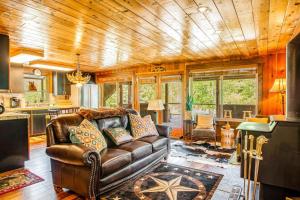 a living room with a leather couch and a kitchen at Teanaway River Lodge in Cle Elum
