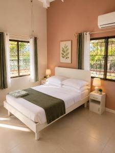 a bedroom with a large white bed with two windows at Paradise Inn in Laborie
