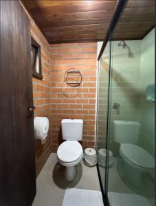 a bathroom with a toilet and a glass shower at Pousada Casarão Gastehaus in Pomerode