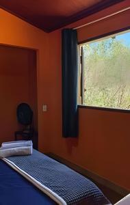 a bed in a room with a window at Chalé Prainha com Cozinha - Valle das Pedras in Sao Jorge
