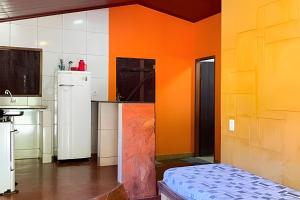 a kitchen with orange walls and white appliances at Chalé Prainha com Cozinha - Valle das Pedras in Sao Jorge