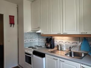 a kitchen with white cabinets and a sink and a stove at Kaksio lähellä keskustaa in Iisalmi +7 photos