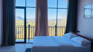 a bedroom with a bed and a balcony with windows at Falcon View in Nuwara Eliya