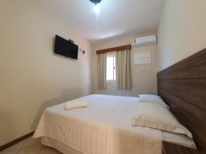 a bedroom with a bed and a television in it at Pousada Acapulco in Bombinhas
