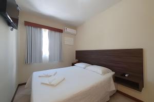 a bedroom with a large white bed and a window at Pousada Acapulco in Bombinhas