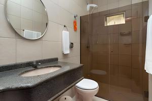 a bathroom with a sink and a toilet and a mirror at Pousada Acapulco in Bombinhas +14 photos