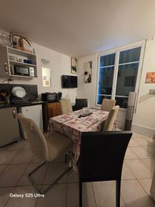 a dining room table and chairs with a table and a kitchen at PR001 3 chambres in Le Blanc-Mesnil