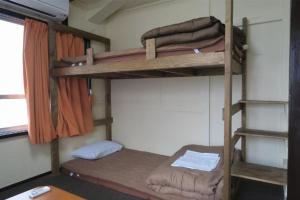 a room with three bunk beds in a room at OKAYAMA Backpackers in Okayama