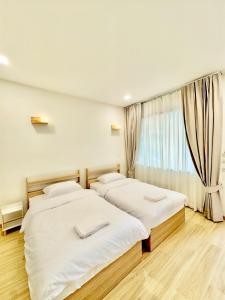 two beds in a room with a window at Minimo Hotel - โรงแรมมินิโม กุมภวาปี in Amphoe Kumphawapi