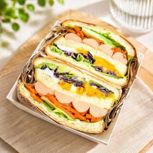 a sandwich in a container on a table at Minimo Hotel - โรงแรมมินิโม กุมภวาปี in Amphoe Kumphawapi