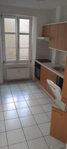 a kitchen with a white tiled floor and two windows at Basel Shared Apartment in Basel