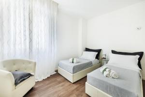 a bedroom with two beds and a couch and a chair at The Iconic Ceccarini - Riviera Collection in Riccione