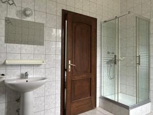 a bathroom with a sink and a shower with a wooden door at Fenyő Liget Vendégház in Balatonlelle +30 photos