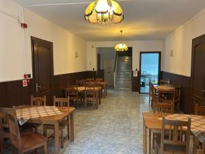 a restaurant with wooden tables and chairs and a chandelier at Fenyő Liget Vendégház in Balatonlelle