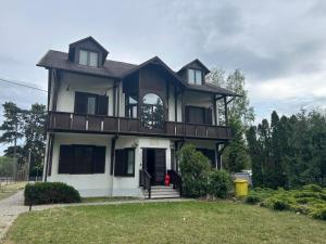 a large house with a balcony on top of it at Fenyő Liget Vendégház in Balatonlelle
