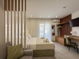 a bedroom with a bed and a desk and a couch at Blue Tree Suites in Pefkochori