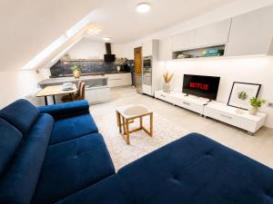 a living room with a blue couch and a kitchen at Elysian apartment 1 in Trenčín