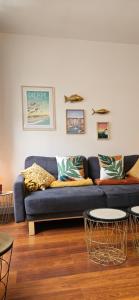 a blue couch in a living room with two tables at Les balcons de Dieppe - appartement 1ER étage - certifié 3 étoiles au cœur de la rue piétonne in Dieppe