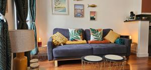 a living room with a blue couch with colorful pillows at Les balcons de Dieppe - appartement 1ER étage - certifié 3 étoiles au cœur de la rue piétonne in Dieppe