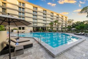 a pool at a hotel with chairs and an umbrella at DoubleTree by Hilton Orlando East - UCF Area in Orlando