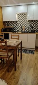 a kitchen with a wooden table and a kitchen with white cabinets at Raj nad Narwią in Zatory