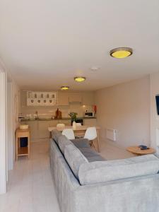 a living room with a gray couch and a kitchen at 105 beach lodge millendreath in Looe