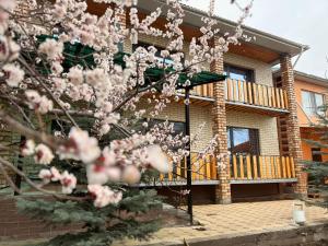 a house with a flowering tree in front of it at Guest House Jekshen in Imeni Karla Marksa