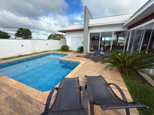 a swimming pool with chairs next to a house at Recanto da Bella in Paranapanema