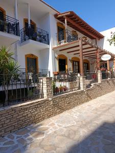 a large white house with a brick retaining wall at Pegasus Hotel in Pythagoreio