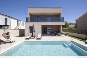 a house with a swimming pool in front of a house at Villa Del Sol near Fažana in Valbandon