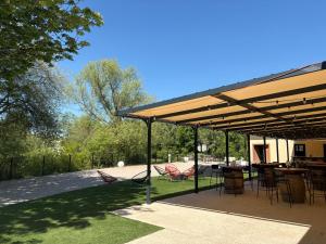 a pavilion with chairs and tables in a yard at Domaine de cézille-Appart hotel le Moulin du lac in Jayat