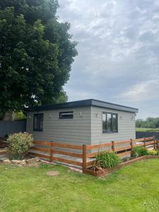 a tiny house in a yard with a fence at Riverside Lodge in Creech Saint Michael
