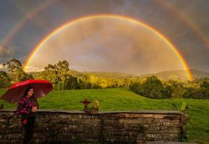 a woman holding an umbrella in front of a rainbow at Aldea Victoria EcoRefugio in Medellín